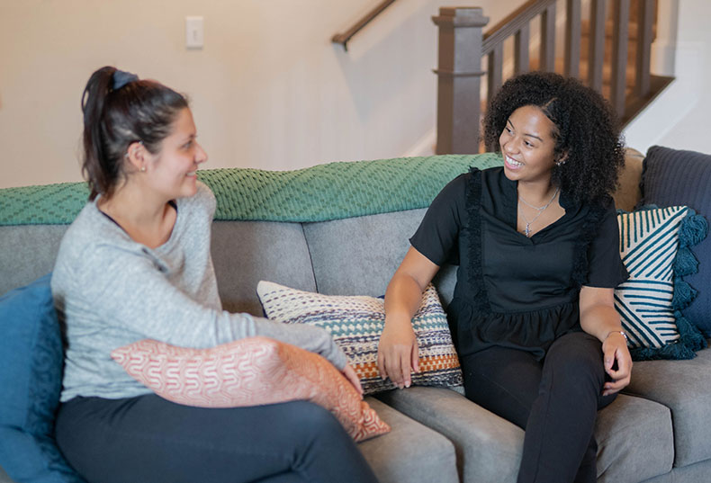 Friends talking and sitting on grey couch